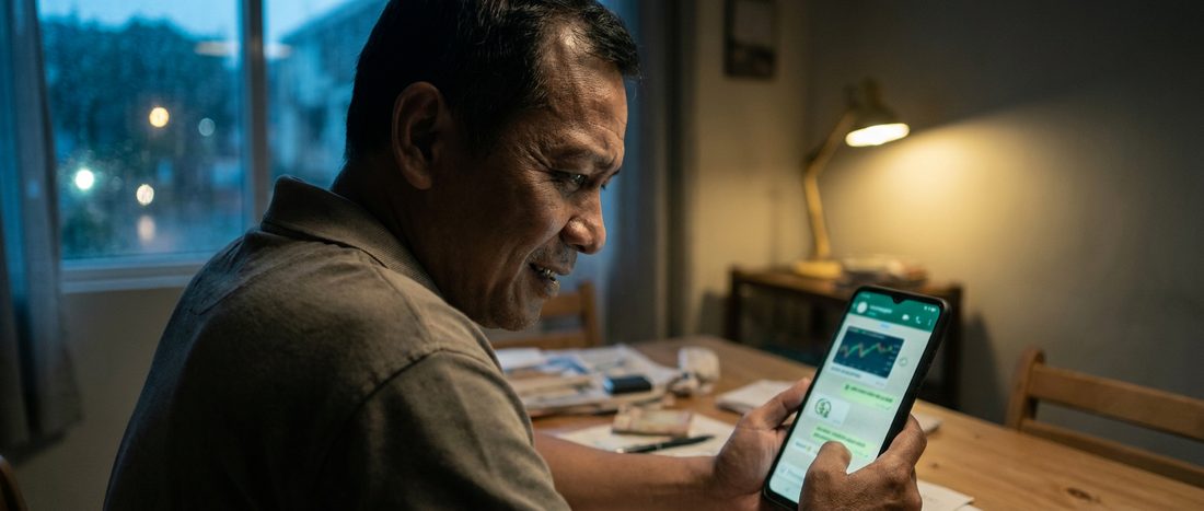A man at home at night reading an investment group chat on his phone
